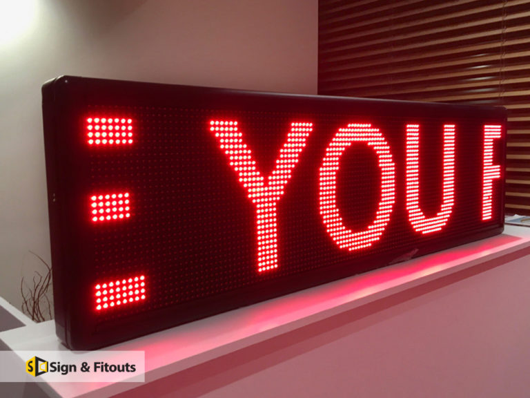 Red LED message sign showing large dot-matrix letters, sitting on a white counter
