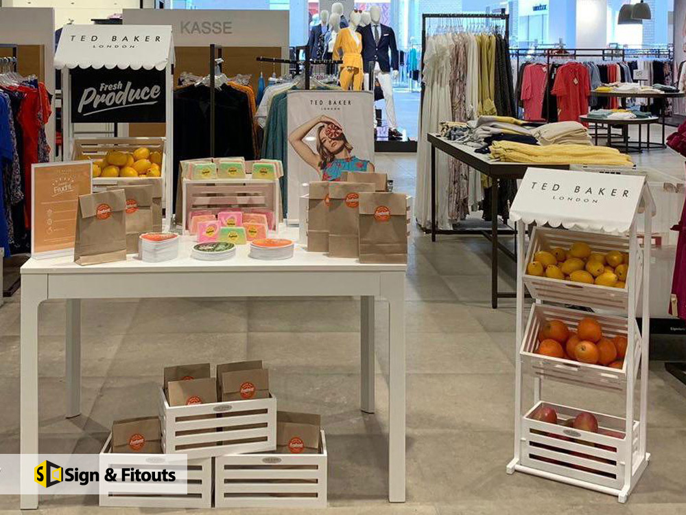 White in-store display stand and crates with Ted Baker branding in a clothing store